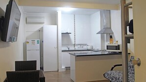 Una cocina compacta con una isla central, un refrigerador y un microondas.