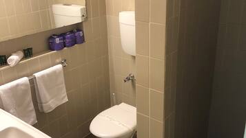 A small bathroom with a toilet, sink, and shower.