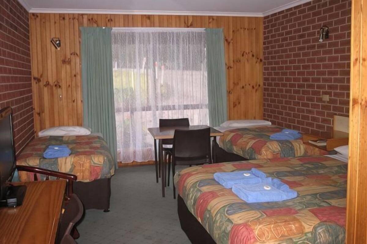 A room with two beds, a desk, and a chair.