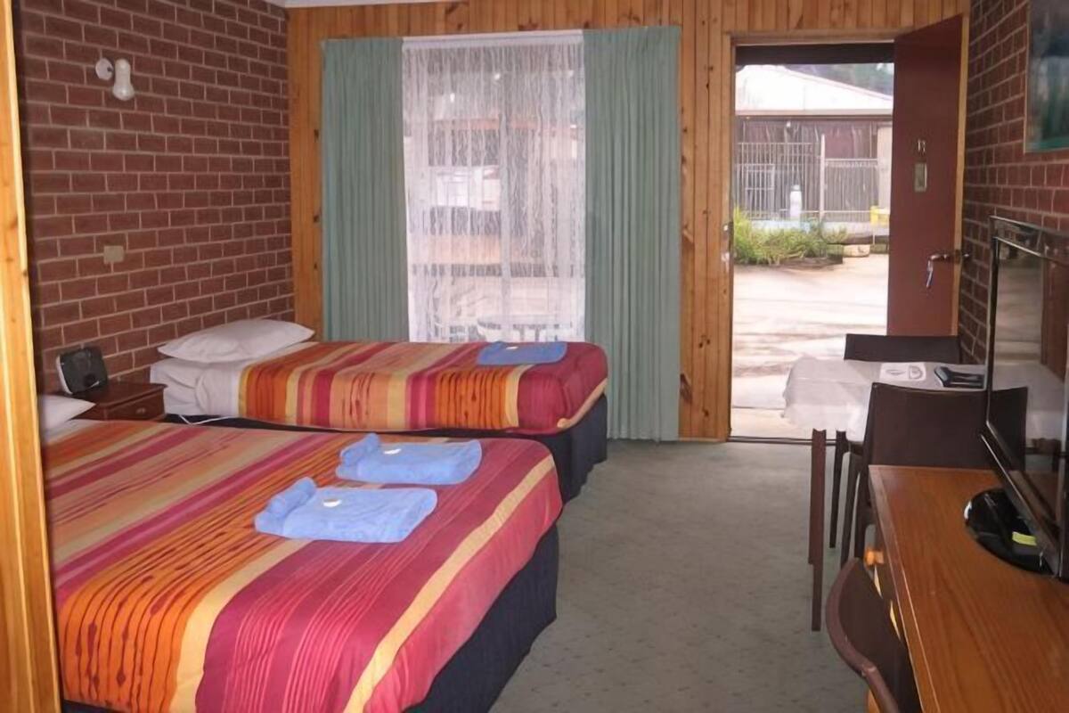 A room with two beds, a desk, and a chair.