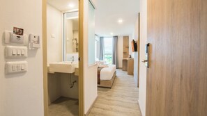 Habitación de hotel moderna con baño, cama y vistas al exterior.