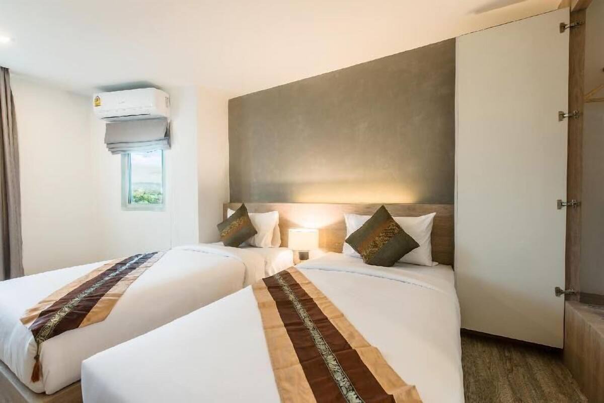 Habitación de hotel con dos camas, un ventanal grande, aire acondicionado y un armario.