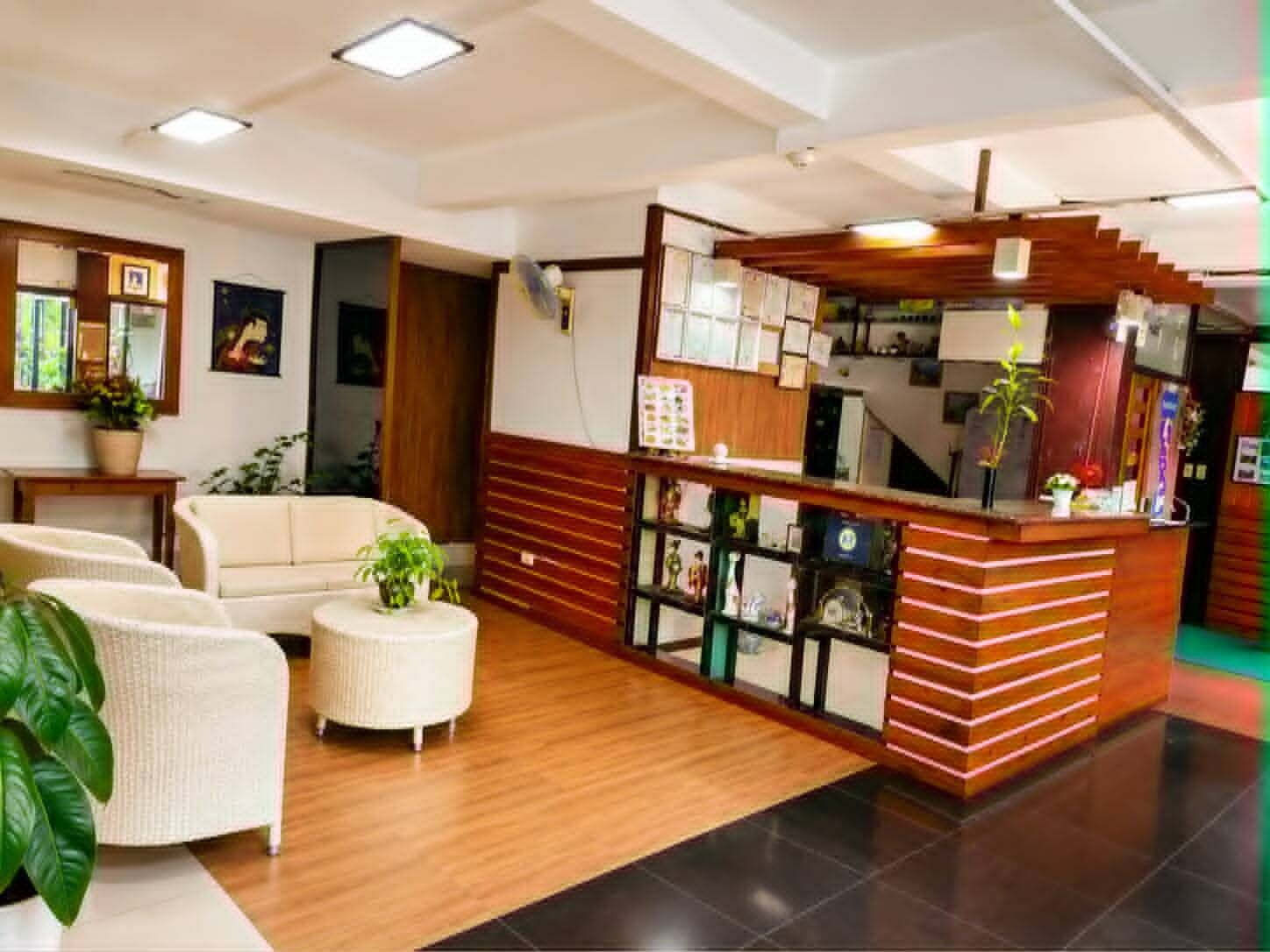 Un vestíbulo de hotel con mostrador de recepción, zona de estar y una escalera.