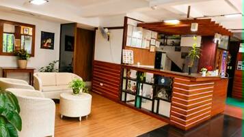 Un vestíbulo de hotel con mostrador de recepción, zona de estar y una escalera.