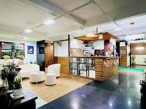 A modern interior with a reception desk, seating area, and a wooden counter. - Axis Pension Hotel (Lapu-Lapu)