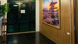 A lobby with a wooden panel wall, a large poster of a pagoda, and a glass door marked 'EXIT ONLY'.