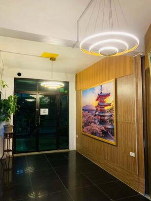 A lobby with a wooden panel wall, a large poster of a pagoda, and a glass door marked 'EXIT ONLY'. - Axis Pension Hotel (Lapu-Lapu)