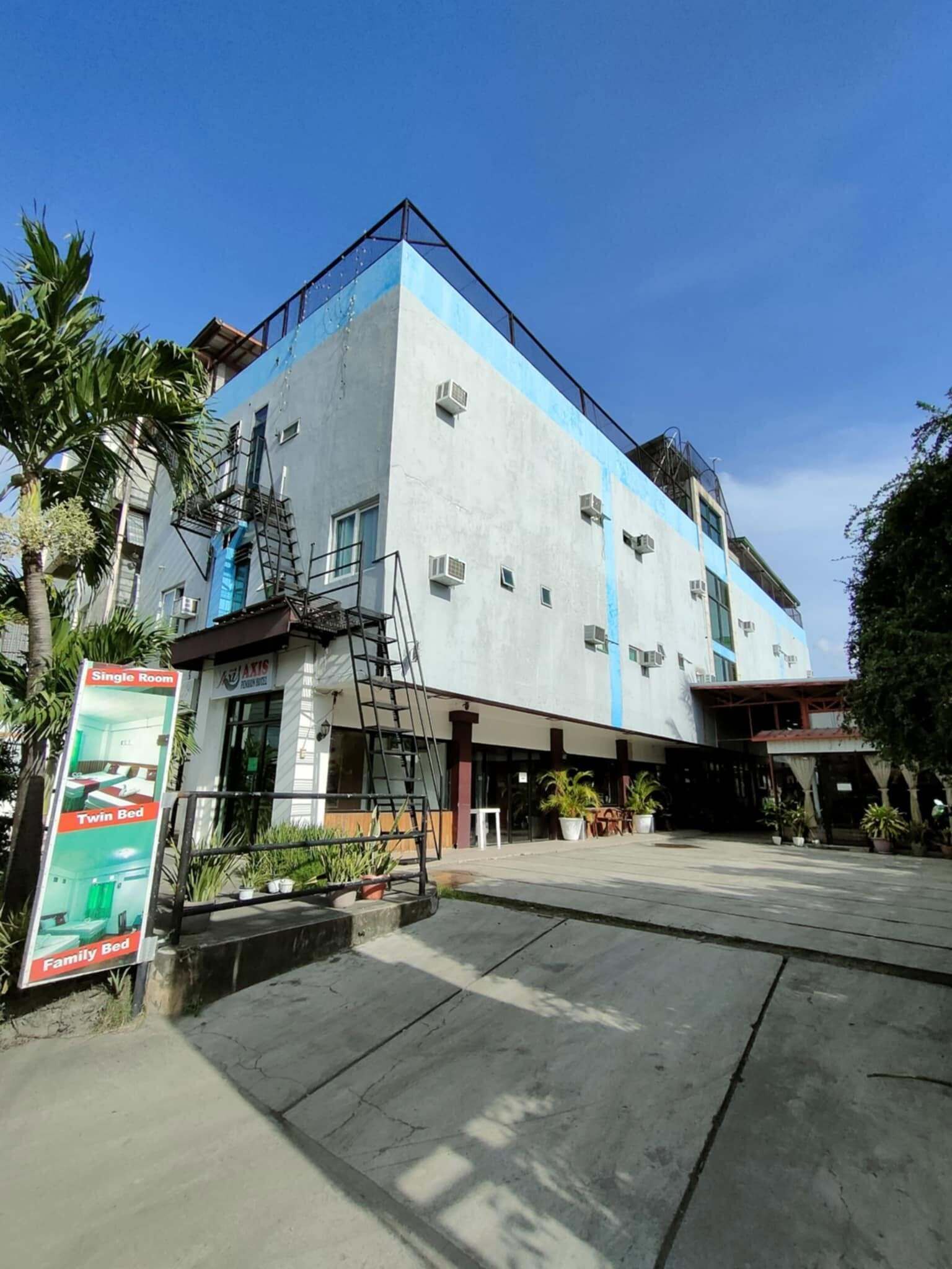 A hotel with a modern design, featuring a blue and white color scheme, a visible staircase, and a signboard with room types.