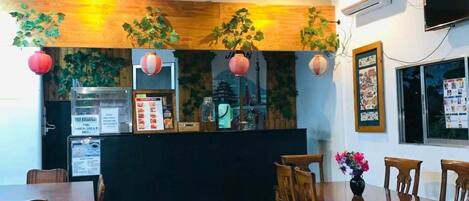 L’intérieur d’un restaurant avec un plafond en bois, un sol carrelé et un comptoir où sont affichés les menus.