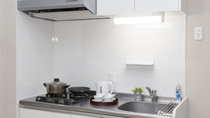 A modern kitchen with white cabinets, a stainless steel stove, a kettle, and a sink. - JESUS SQUARE Nippombashi (Osaka)