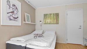 A bedroom with a bed, a door, and wall art including a bird illustration and a forest painting. - Brekstad Gjestehus (Orland)