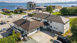 A modern building with a flat roof, large windows, and a parking area in front. - Brekstad Gjestehus (Orland)