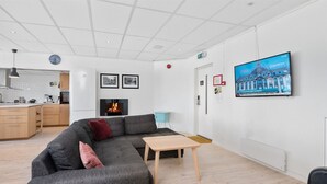 A modern living room with a grey sectional sofa, a small wooden table, and a fireplace. - Brekstad Gjestehus (Orland)