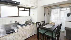 Cocina compacta con estufa integrada, un lavamanos y un comedor con mesa y sillas.