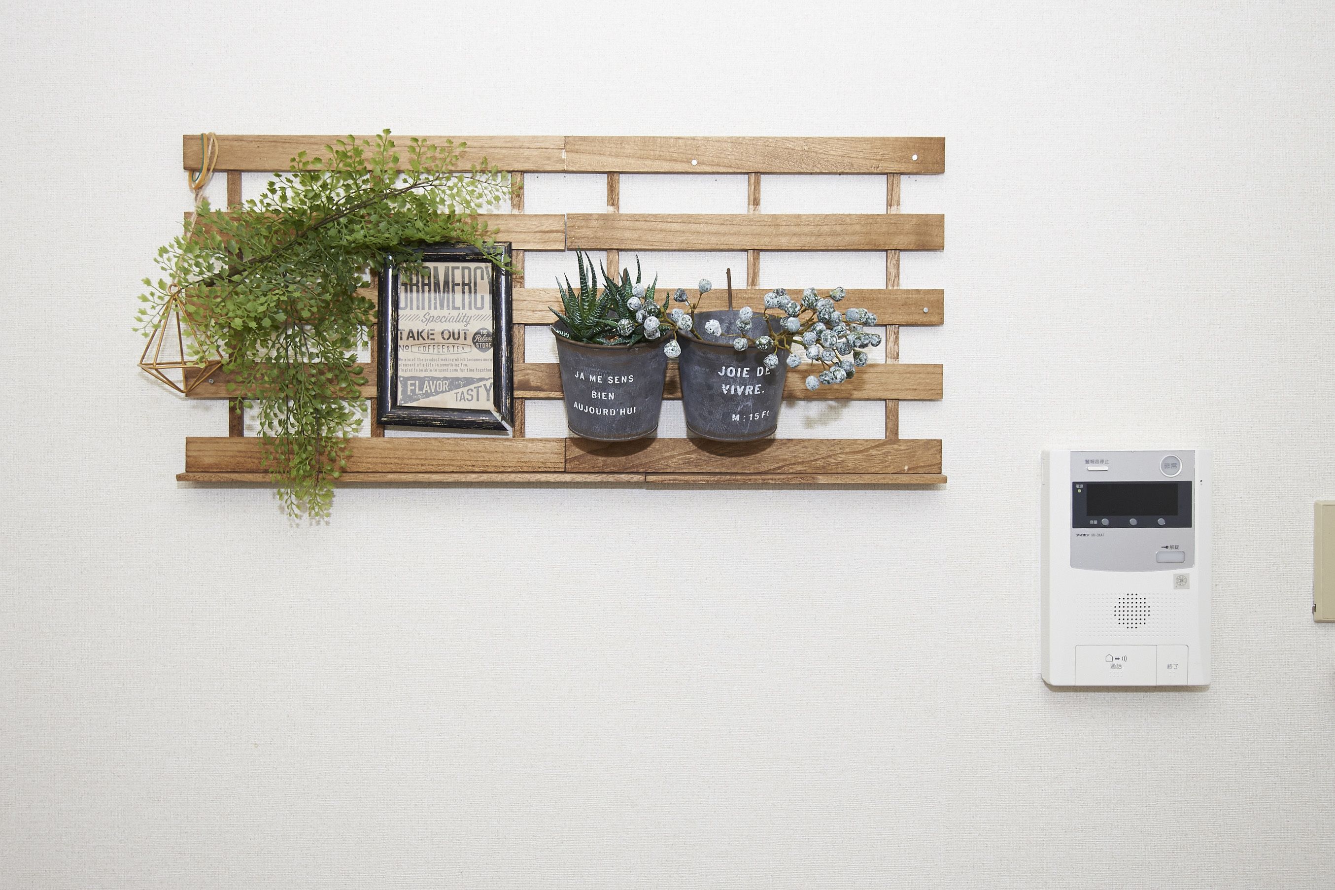 Een houten plank met twee planten in potten en een lijst met een bordje.