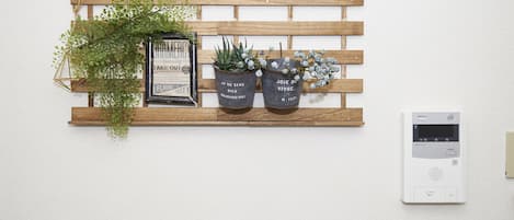 A wooden shelf with two potted plants and a framed sign.