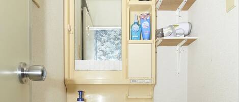 A compact bathroom with a sink, mirror, and storage cabinet.