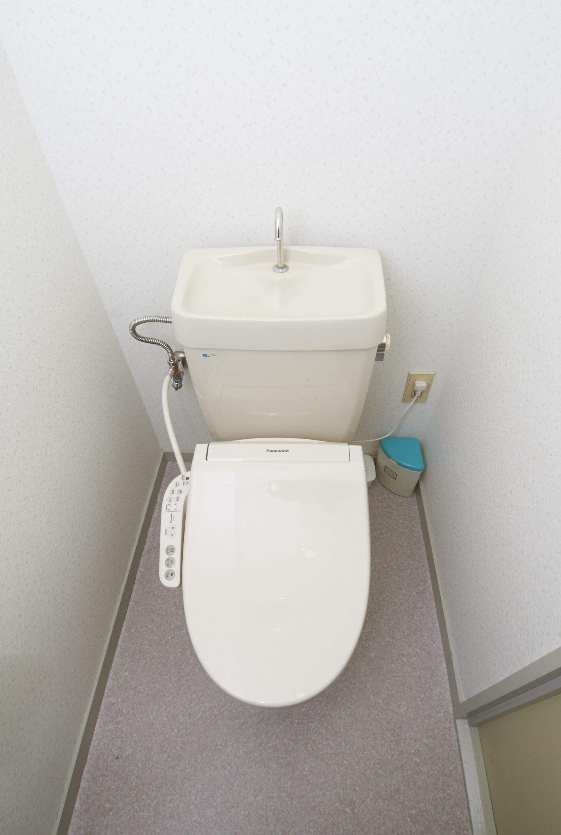 Un baño pequeño con inodoro, lavamanos y un cubo de basura.