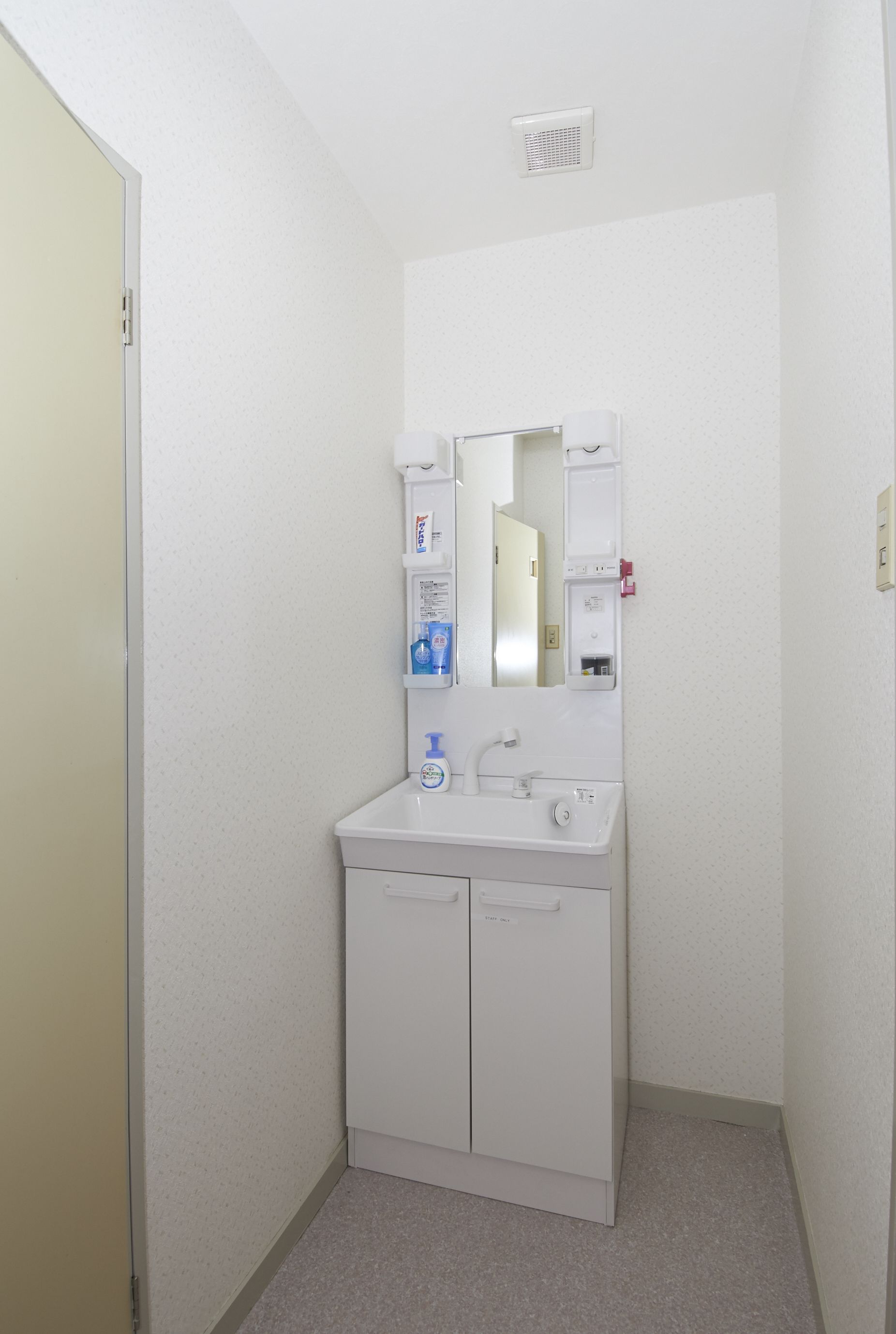 A small, white bathroom with a sink, mirror, and storage cabinet.