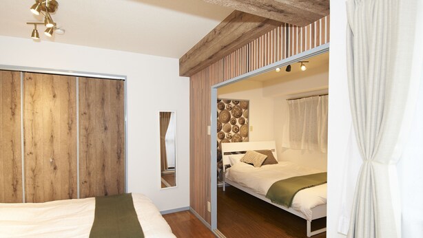 Un dormitorio con un armario de madera, una puerta de armario con espejo y una cama con un plaid verde.