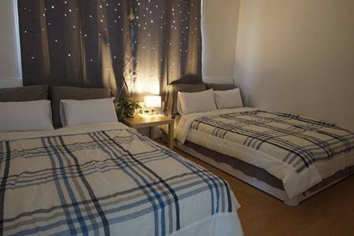 A bedroom with two beds, a nightstand, and a lamp.