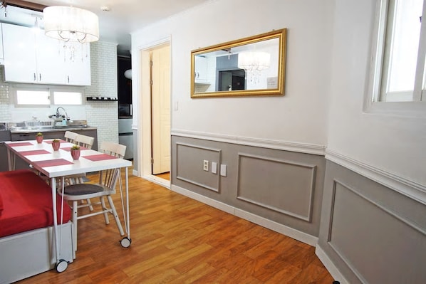 A compact kitchen with white cabinets, a dining table with chairs, and a chandelier.