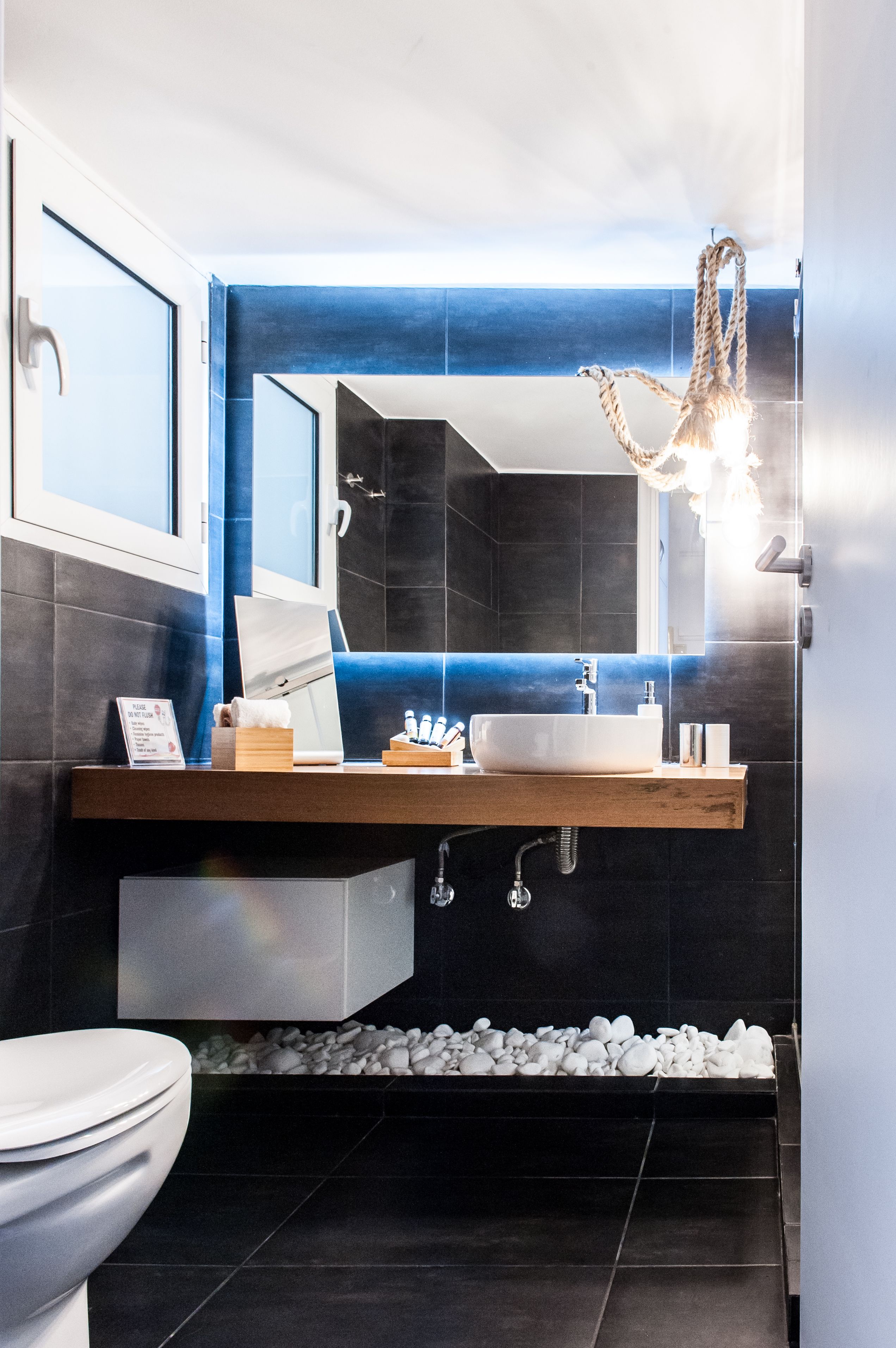 Ein modernes Badezimmer mit einem großen Spiegel, einem weißen Waschbecken und einer Holz-Waschkommode.