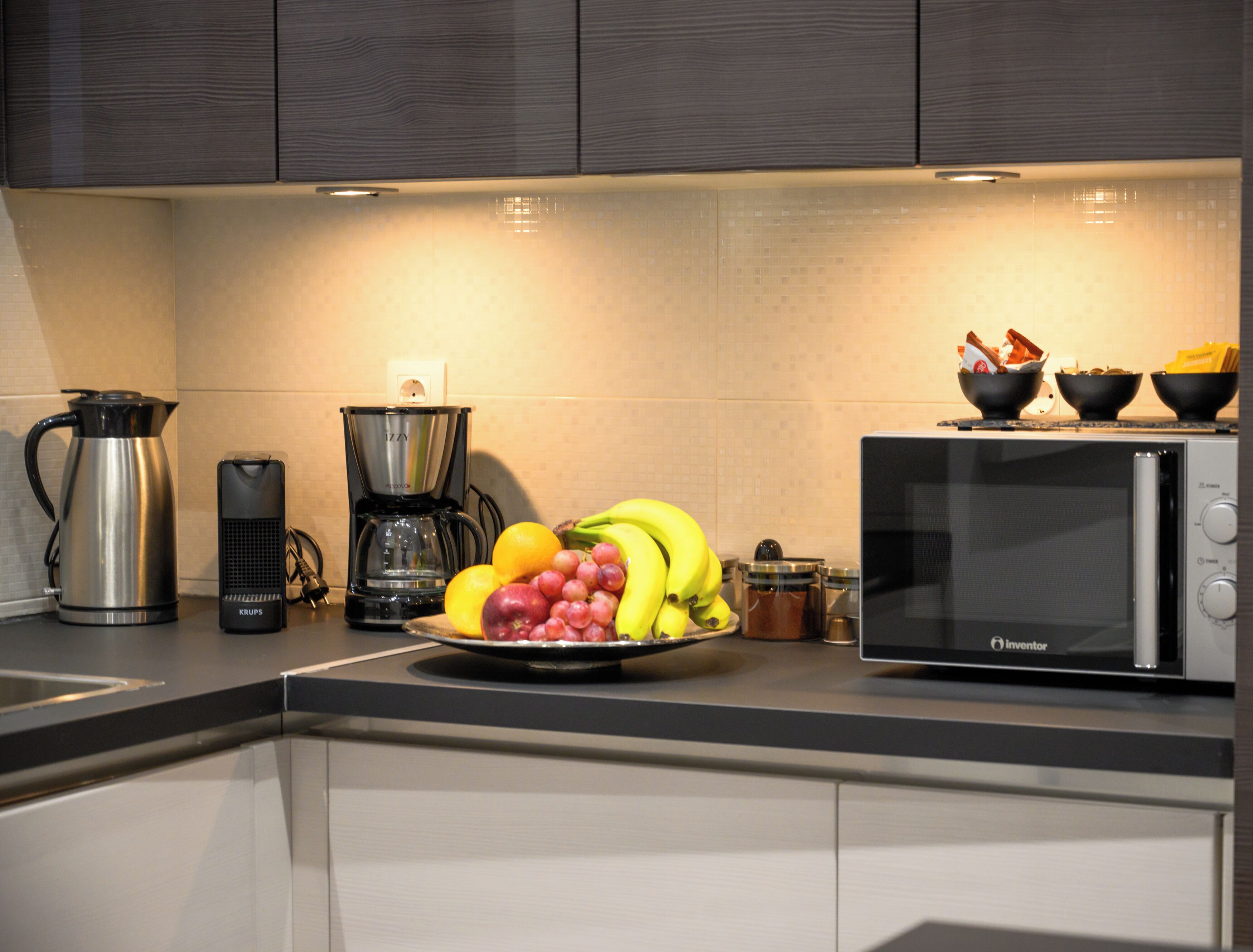 A kitchen with a coffee maker, a microwave, and a fruit bowl on the counter.