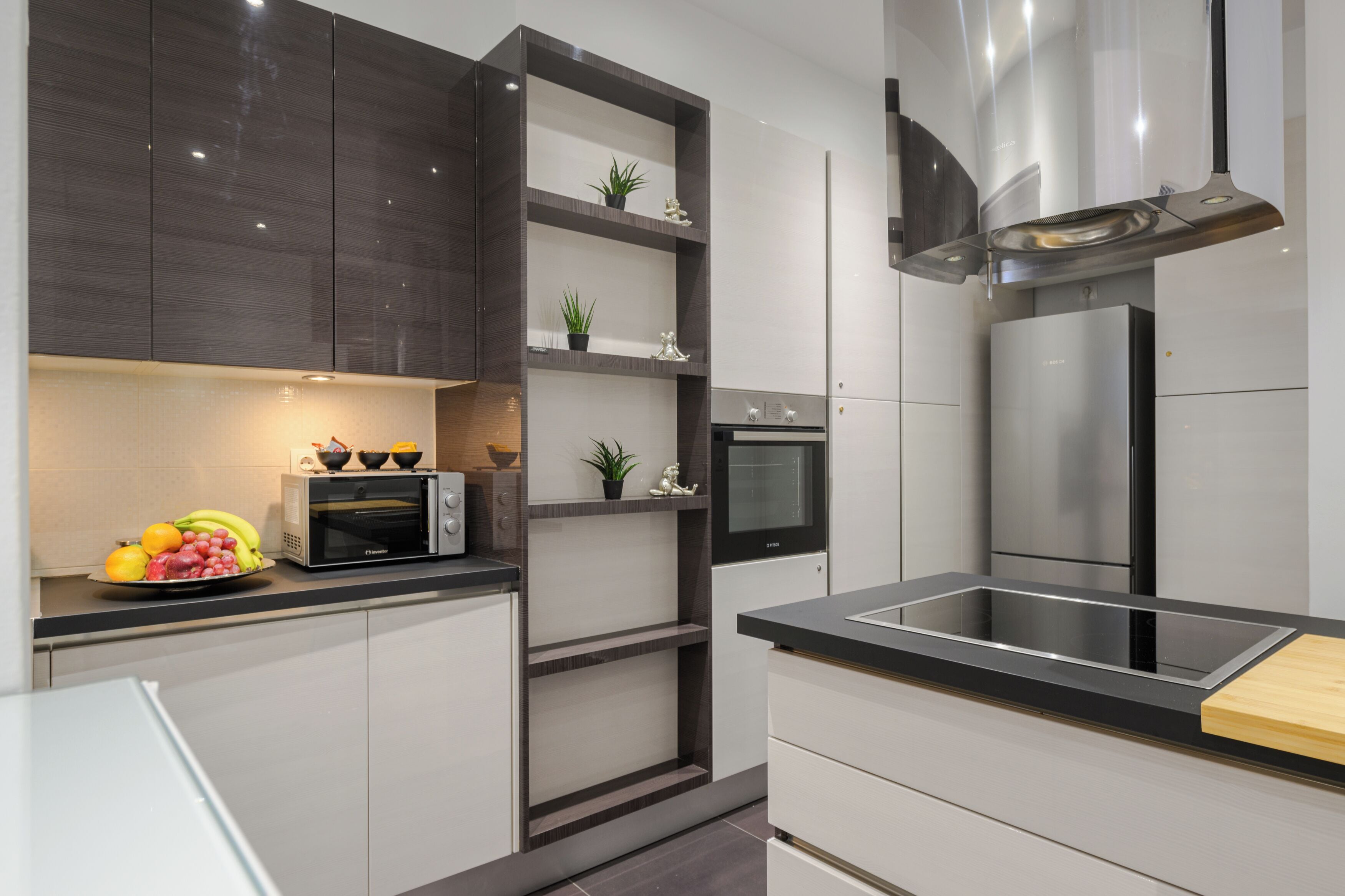 A modern kitchen with a built-in oven, microwave, and stainless steel refrigerator.
