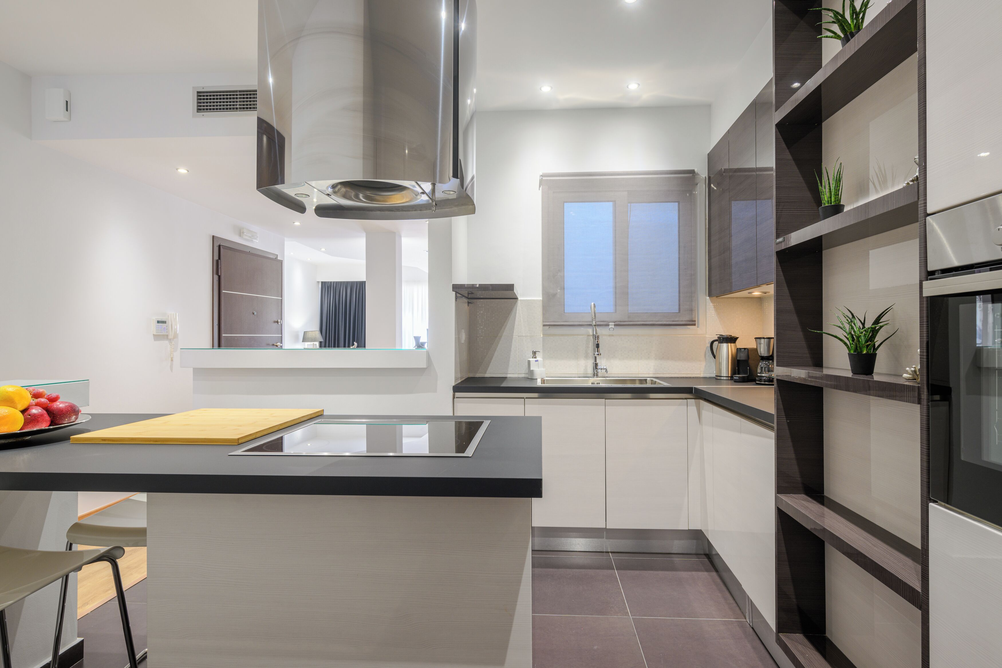 A modern kitchen with a central island, built-in appliances, and a window providing natural light.