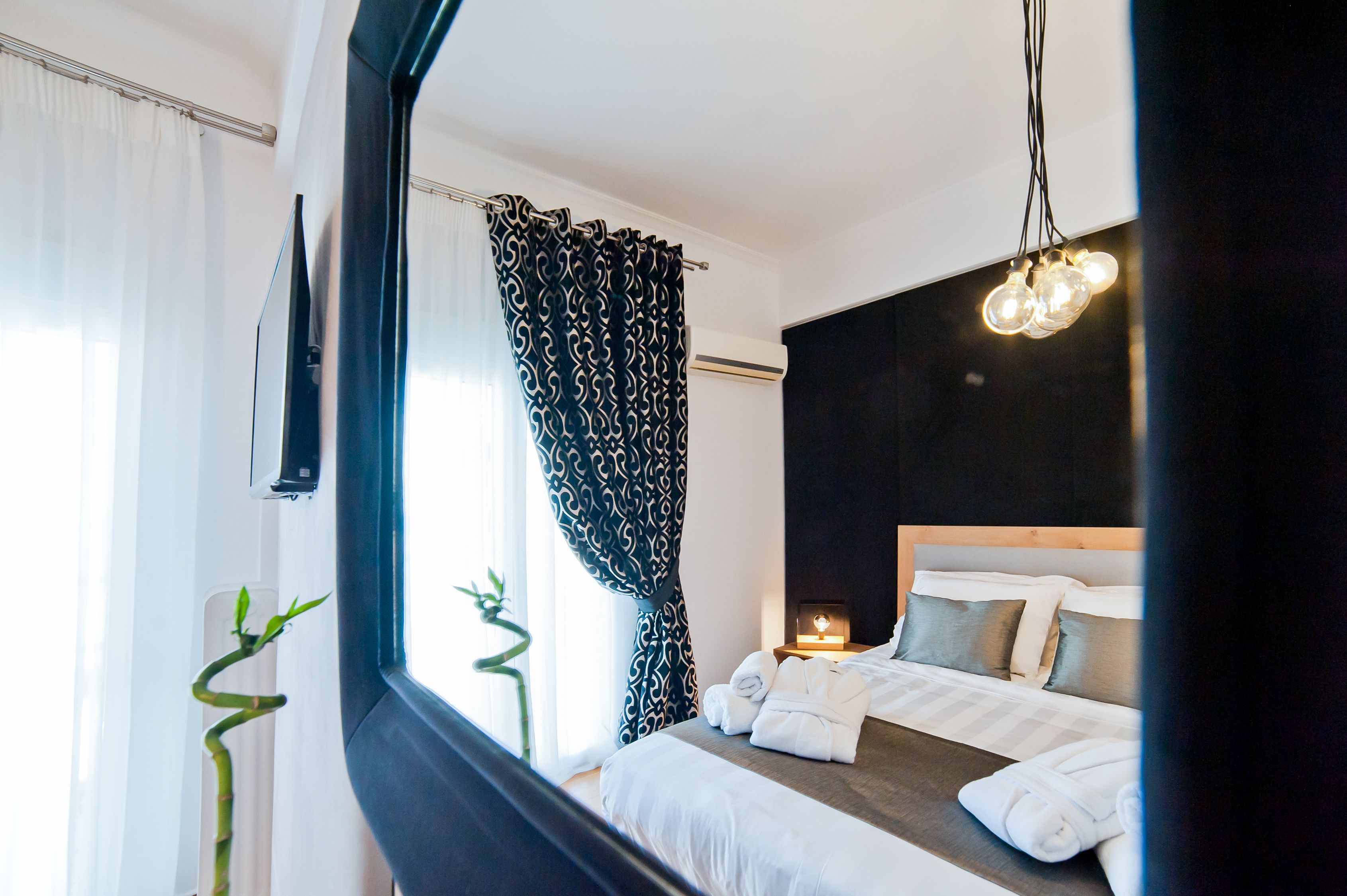 A modern hotel room with a bed, bedside table, and a nightstand with a lamp.