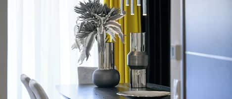 Een eettafel met een bloemenvaas, een metalen vaas en een zwart bord.