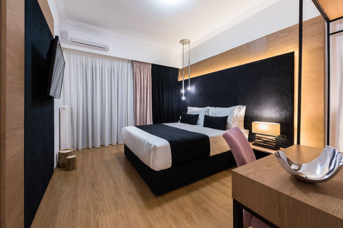 Une chambre d’hôtel moderne avec un grand lit, une table de chevet et un bureau avec une chaise.