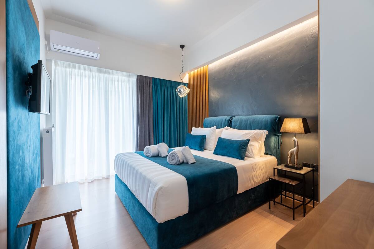 Une chambre d’hôtel moderne équipée d’un grand lit, d’un téléviseur à écran plat, d’un bureau et d’une lampe.