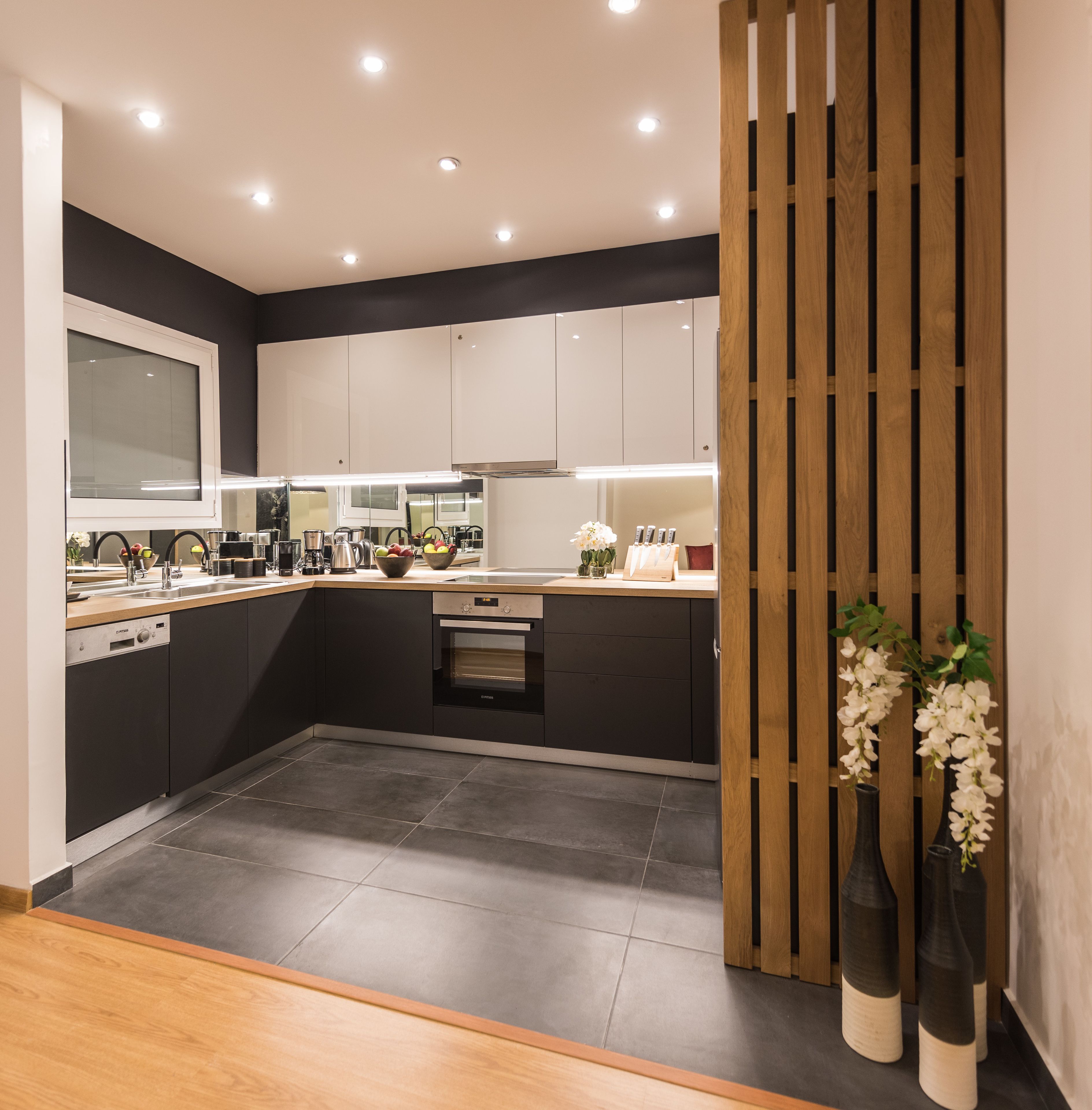 A modern kitchen with dark cabinetry, a built-in oven, and a wooden divider.