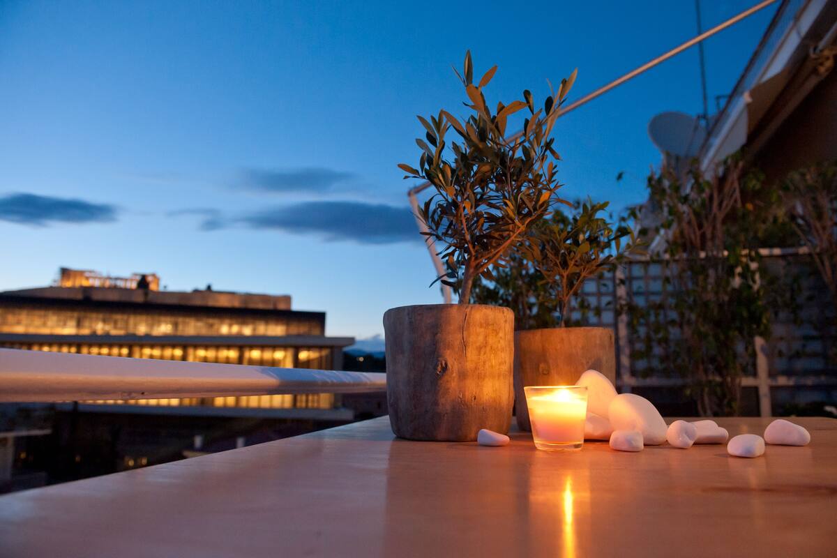 Une terrasse sur le toit agrémentée d’un pot de fleurs, d’une bougie et de quelques pierres polies.