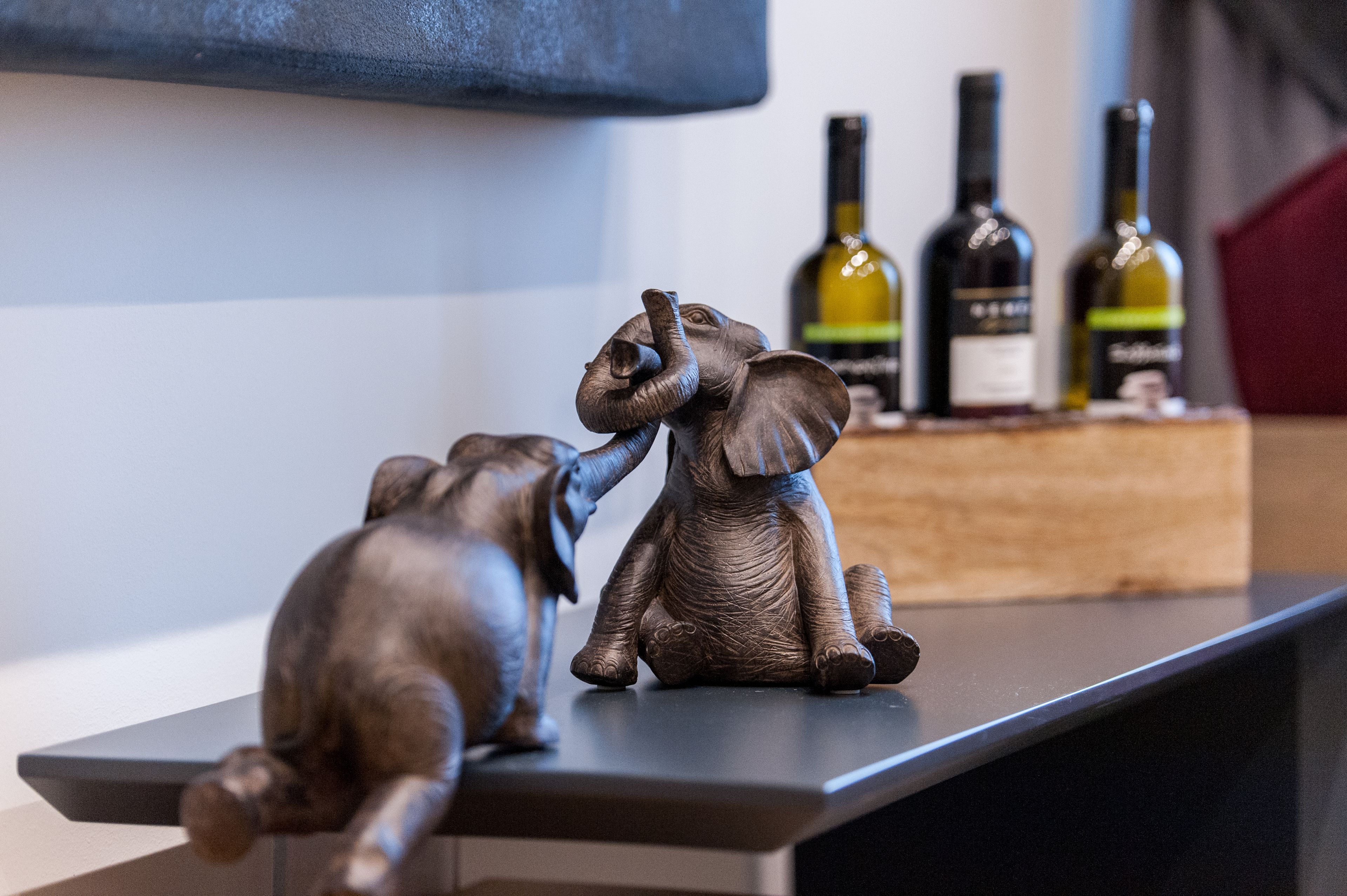 Una repisa con dos figuritas de elefantes y tres botellas de vino.