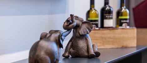 A shelf with two elephant figurines and three wine bottles.