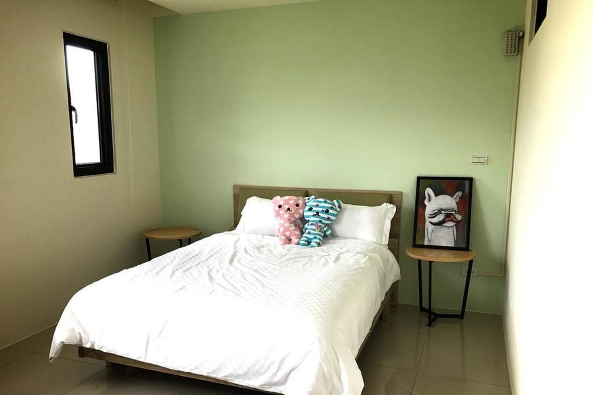 A bedroom with a bed, two bedside tables, a window, and a wall-mounted picture.