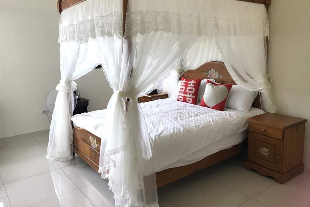 A four-poster canopy bed with a wooden frame and white bedding.