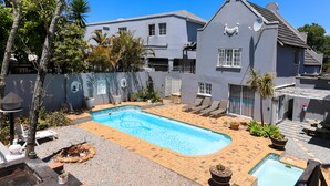 A residential property with a swimming pool, outdoor seating, and a fenced garden area. - George Lodge International (George)