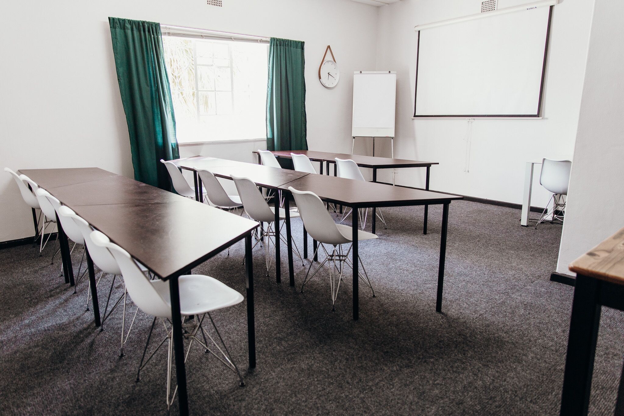 A conference room with a whiteboard, a clock, and a projector screen.