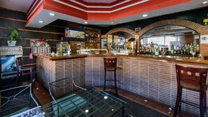 A bar with a brick counter, stools, and a glass table.