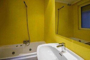 A bathroom with a bathtub, a sink, and a window. - Hotel Rio Cea (Valderrueda)