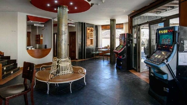 A lobby with a reception desk, a bench, and a gaming machine.