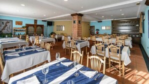 A restaurant with multiple tables and chairs, a brick column, and a tiled floor.