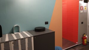 A restroom with a striped cabinet, a round trash bin, and a fire extinguisher. - Tiburtina Suites (Rome)