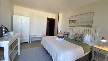 A bedroom with a bed, bedside tables, a desk, a wardrobe, and a painting on the wall.