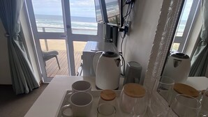 A hotel room with a large window offering a view of the beach and ocean. - Sea Paradise (Wilderness)