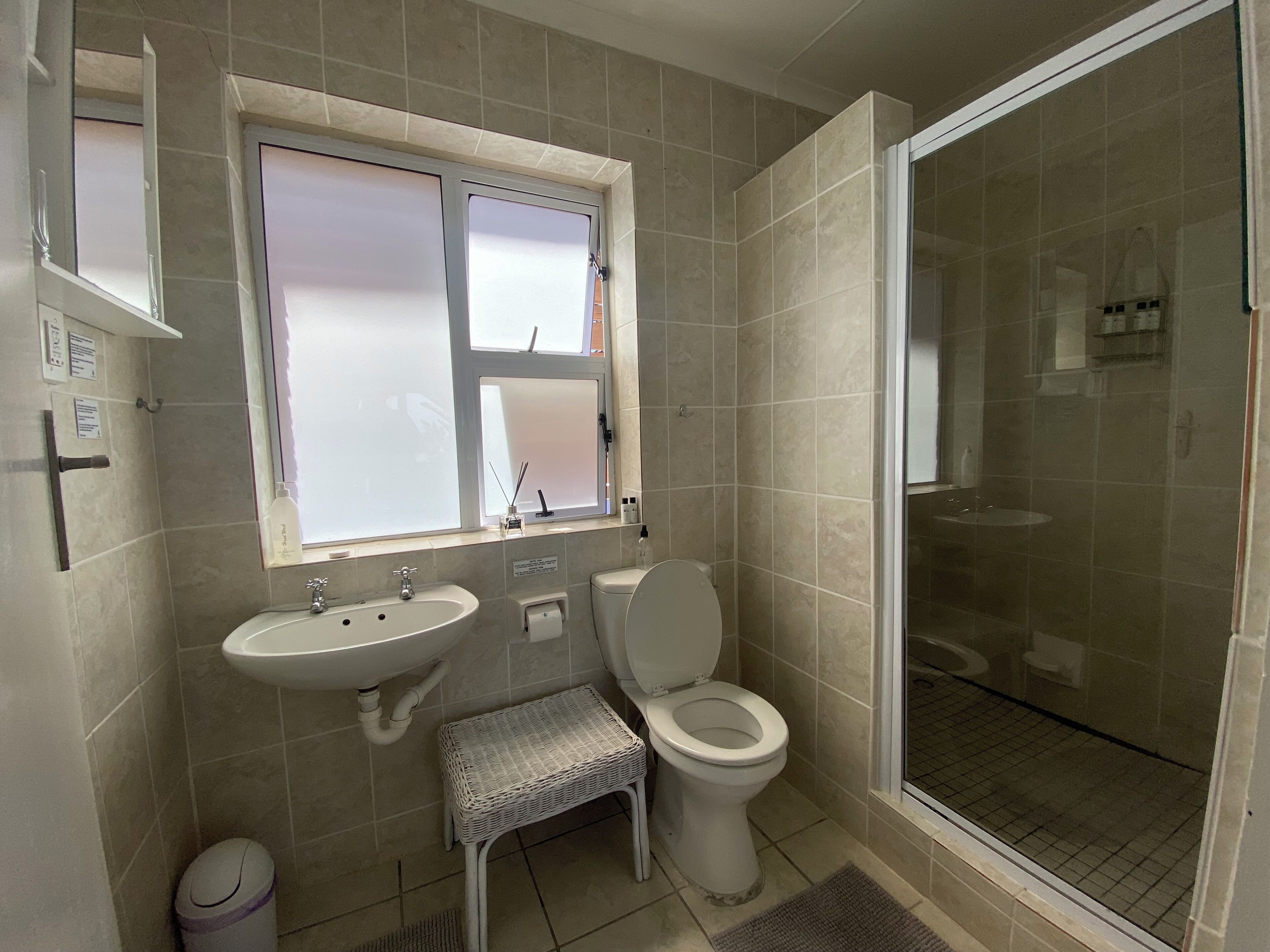 A bathroom with a shower, toilet, sink, and a small step stool.